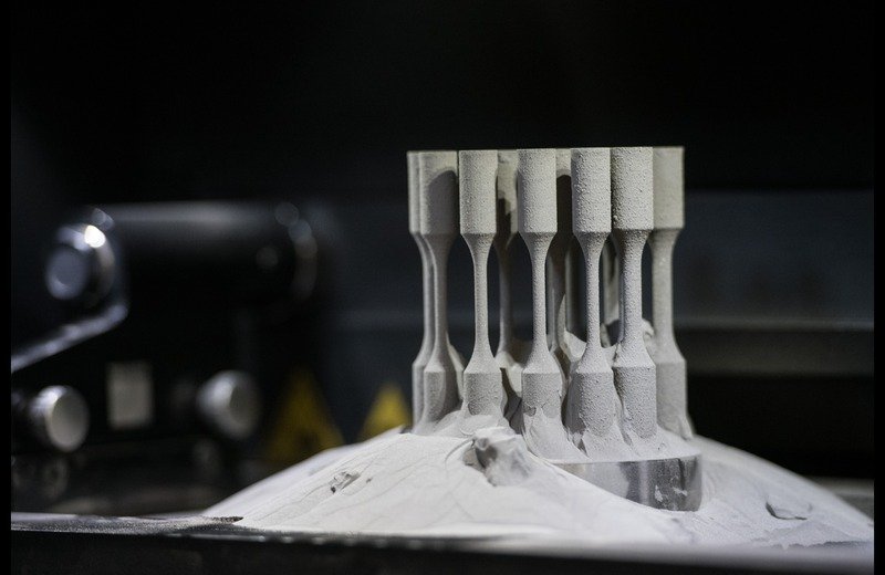 Selective Laser Melting (SLM) metal 3D printing build plate with specimens rising from titanium powder bed